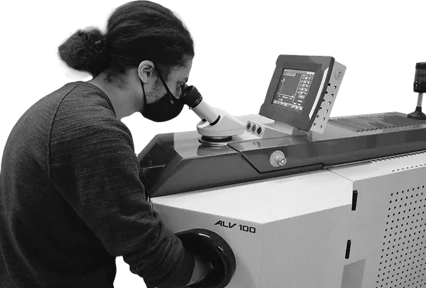 A person looks into the eyepiece of a machine while working.